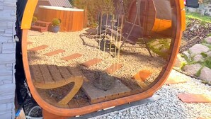 A circular mirror reflecting a garden with a wooden structure, a potted plant, and a metal chair. - Mountain Chalet for 20 with Wellness, Sauna & Hot Tub — Ski-in/Ski-out (Martin)
