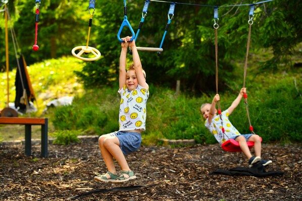 Children playing on a playground with swings and monkey bars.