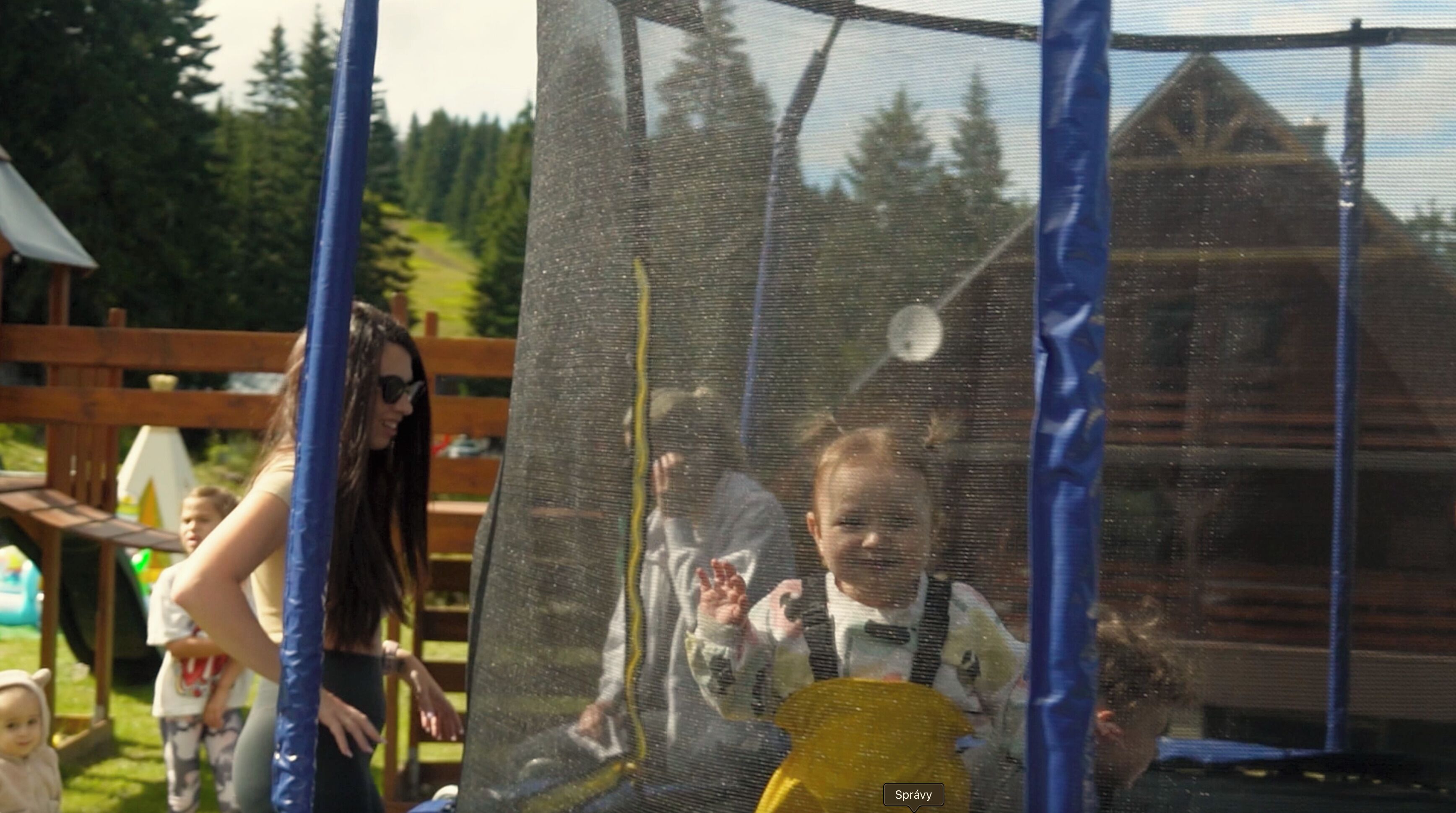 Eine Holzhütte mit eingezäuntem Garten, einem Spielplatz und blauem Himmel.