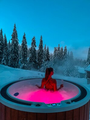Henkilö porealtaassa, taustalla lumipeitteinen metsä.