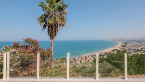 A coastal view with a palm tree, beach, and residential area. - Miramare Suites - Camera Ardesia (Vasto)