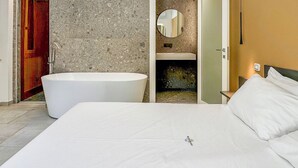 A modern bedroom with a large bed, a bathtub, and a bathroom with a mirror and sink. - Miramare Suites - Camera  Ardesia (Vasto)
