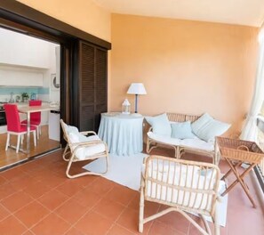 A balcony with wicker furniture, a table, and a lamp. - Sea View Apartment · Porto Rotondo Center · 3BR · Terrace · Walking Distance to the Marina (Porto Rotondo)