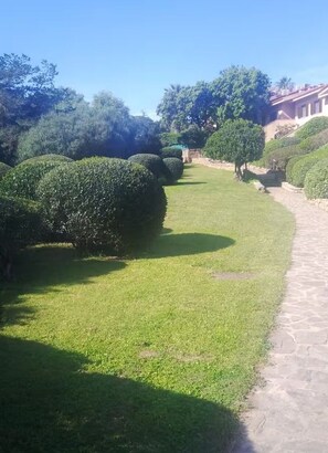 A well-maintained garden with neatly trimmed hedges and a paved walkway. - Sea View Apartment · Porto Rotondo Center · 3BR · Terrace · Walking Distance to the Marina (Porto Rotondo)