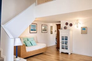Un dormitorio con cama, lámpara, aparador y cuadros en la pared.