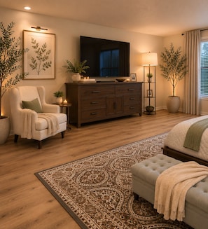 Un dormitorio moderno con una cama grande, un sofá, un armario de madera y una televisión.