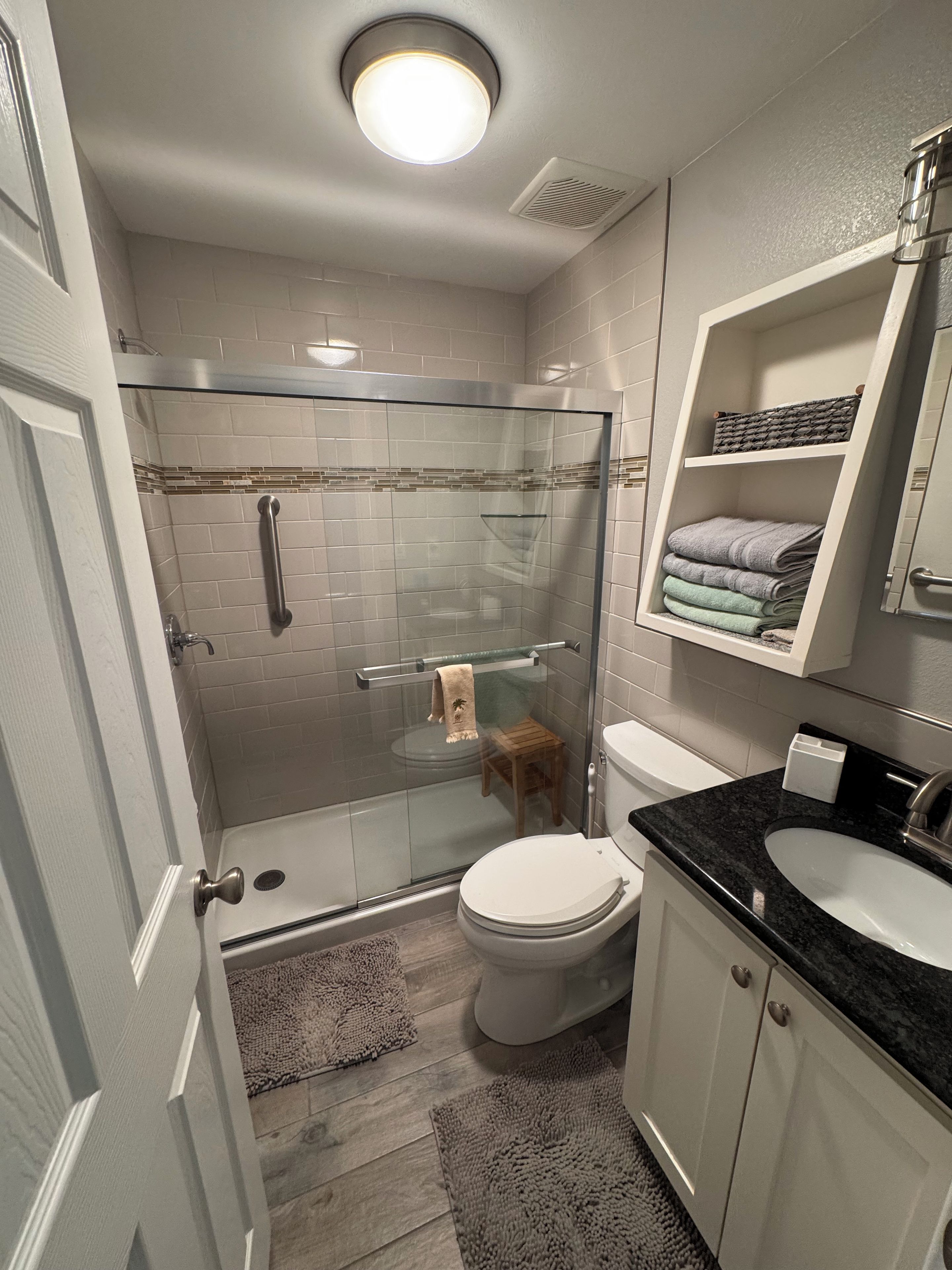 Ein modernes Badezimmer mit Duschkabine, Toilette, Waschbecken und Handtuchhalter.