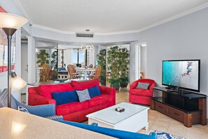 Een moderne woonkamer met een rode bank, een witte salontafel en een flatscreen televisie.