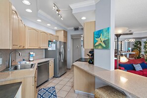 Een moderne keuken met inbouwapparatuur, een eethoek met een rode bank en een schilderij aan de muur.