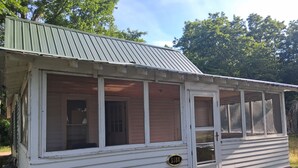 Ein einstöckiges Gebäude mit Veranda, Tür und Fenster mit einer Nummer.'