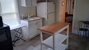 Eine kleine Küche mit Spüle, Kühlschrank und einem Holztisch.