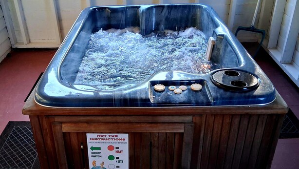 Ein Whirlpool mit Anleitung, eine Holzbank und ein gemustertes Teppich.