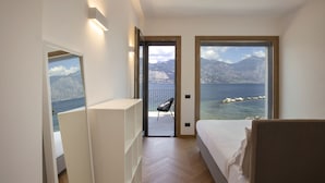 A bedroom with a bed, a chair, and a view of the sea and mountains. - Villa Locchi with private Pier (Malcesine)