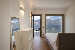 A bedroom with a bed, a chair, and a view of the sea and mountains. - Villa Locchi with private Pier (Malcesine)