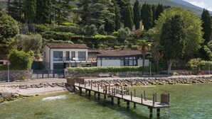 A lakeside property with a dock, a house with a balcony, and surrounding greenery. - Villa Locchi with private Pier (Malcesine)