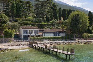 A lakeside property with a dock, a house with a balcony, and surrounding greenery. - Villa Locchi with private Pier (Malcesine)