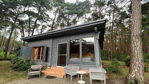 Eine Hütte mit Veranda, Sitzgelegenheiten im Freien und Blick auf den umliegenden Wald.