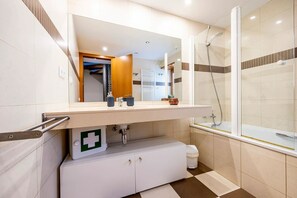 Une salle de bain moderne équipée d’une douche, d’un lavabo avec un miroir, d’un meuble sous le lavabo et d’une trousse de premiers secours.