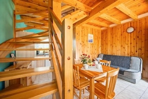 A wooden interior with a dining table, chairs, a sofa, and a staircase. - Two-story holiday homes with terraces, playground (Mielno)