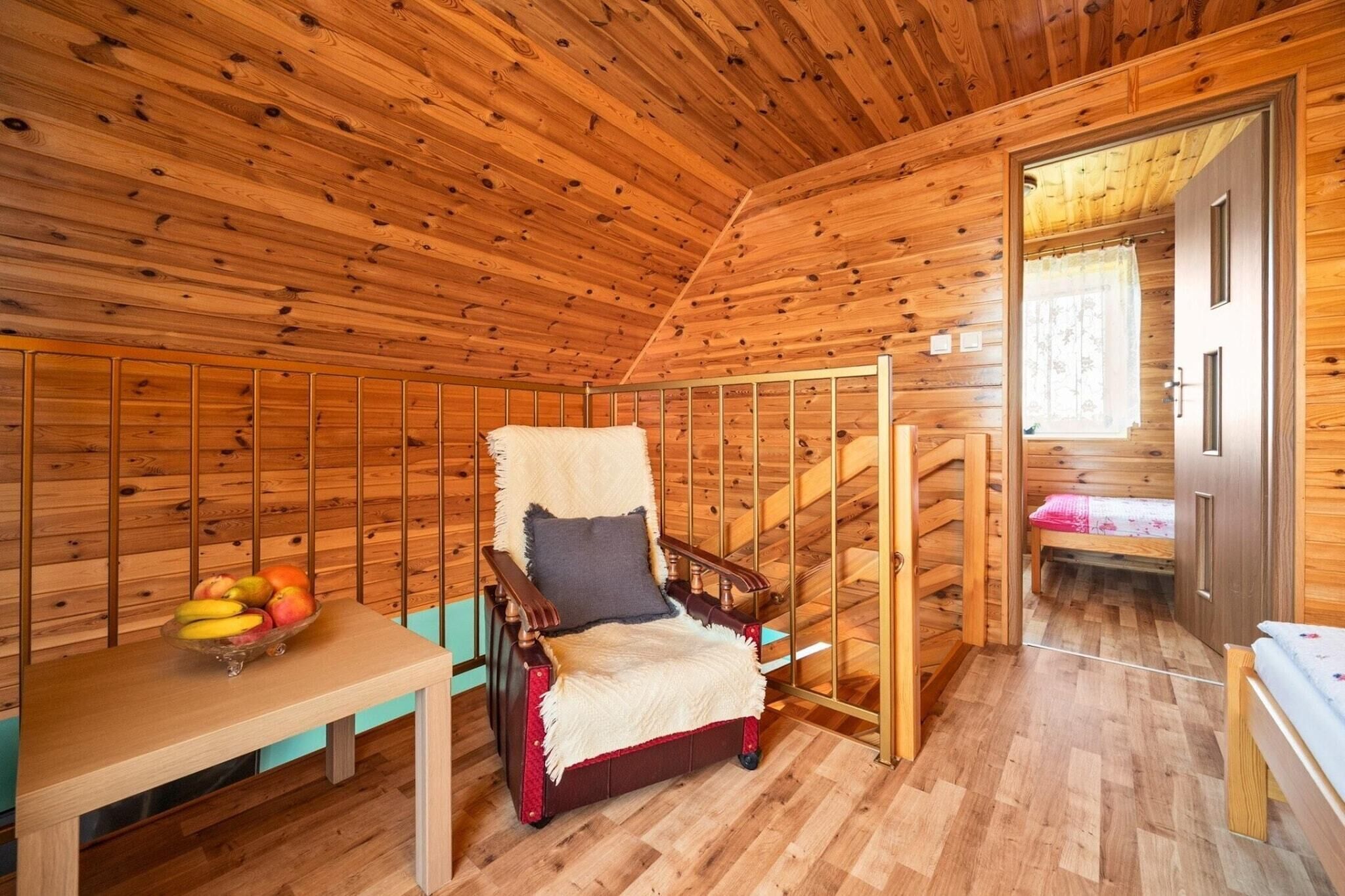Ein Holzblockhaus-Interieur mit einem Holzstuhl, einem Tisch mit Obst und einer Treppe.