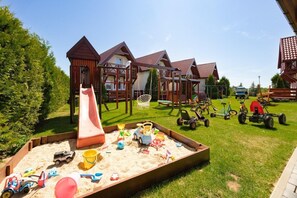 A playground with a slide, swings, and sand play area. - Two-story holiday homes with terraces, playground (Mielno)