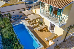 Ein Poolbereich auf dem Dach mit Liegestühlen und Sonnenschirmen, ein Schwimmbecken und ein Balkon mit Geländer.