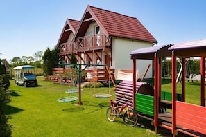 Ein zweistöckiges Haus mit rotem Dach, einer Veranda und einer Schaukel.