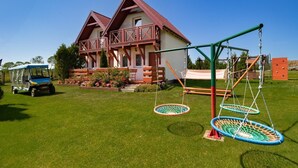 Une maison avec un balcon, une balançoire et une pelouse.