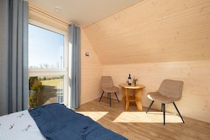 A room with a bed, two chairs, a small table, and a window with curtains. - Year-round holiday home with fireplace and terrace (Mielno)