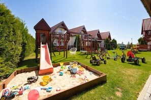 A playground with a slide, swings, and sandpit with toys. - Year-round holiday home with fireplace and terrace (Mielno)