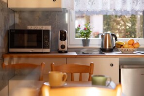 A kitchen with a microwave, a coffee maker, a kettle, and a fruit bowl on the counter. - Year-round holiday home with fireplace and terrace (Mielno)