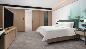 Ett modernt hotellrum med en stor säng, en tv, ett skrivbord med en telefon och en garderob.
