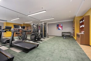 Une salle de sport équipée de tapis de course, de vélos elliptiques et d'appareils de musculation.