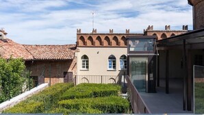 Un edificio con fachada de ladrillo, ventanas arqueadas y una extensión de vidrio moderna.