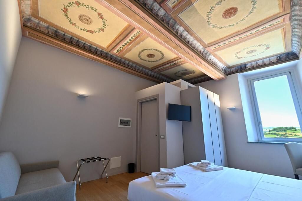 Camera da letto con un letto, una televisione, una finestra e un soffitto con decorazioni.