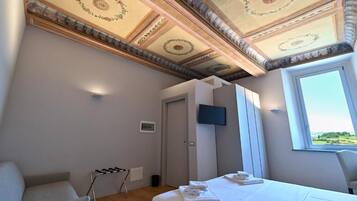Camera da letto con un letto, una televisione, una finestra e un soffitto con decorazioni.