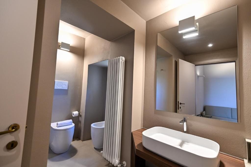 Un baño moderno con inodoro, bidé y un lavamanos grande y rectangular.