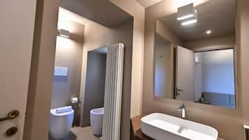 Un baño moderno con inodoro, bidé y un lavamanos grande y rectangular.