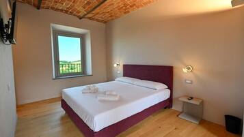 A bedroom with a bed, a window, a nightstand, and a brick ceiling.