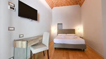 A bedroom with a bed, a desk, and a TV mounted on the wall.