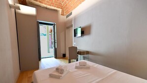 Una habitación de hotel con una cama, televisor, escritorio y una silla.
