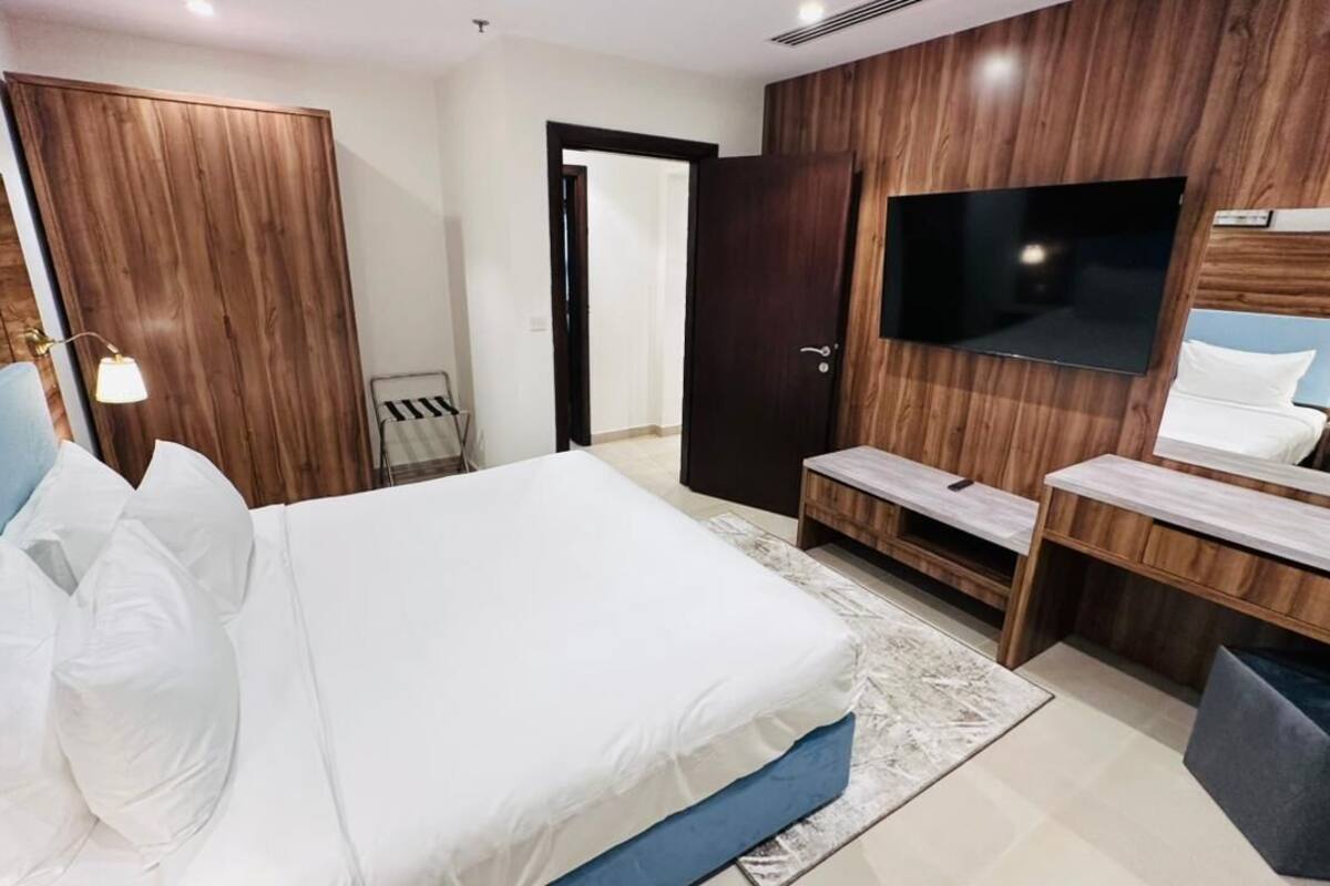 Un dormitorio con cama, televisor, espejo y paneles de madera.