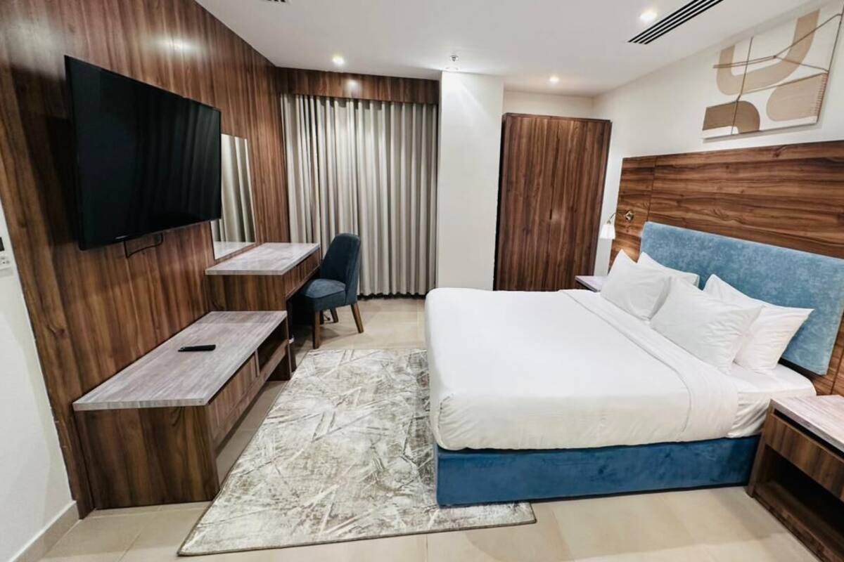 Una habitación de hotel moderna con una cama grande, un televisor, un escritorio y una silla.