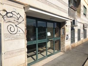 Eine Gebäudefassade mit einer großen Glasdoor, Steinmauern und Graffiti.