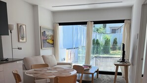 A modern living room with a dining area, a sofa, a TV, and a view of the outside. - 2 Beds Garden Condo in Fort Greene (Brooklyn)