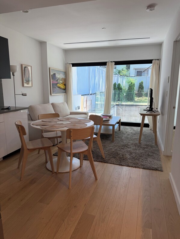 Un salon moderne comprenant un coin repas, un canapé, un téléviseur et une vue sur l’extérieur.