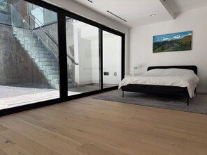 A bedroom with a bed, a painting, and a view of a staircase.