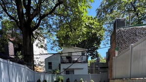 A concrete staircase leading down to a covered area with a metal railing, surrounded by trees and a building in the background. - 2 Beds Garden Condo in Fort Greene (Brooklyn)