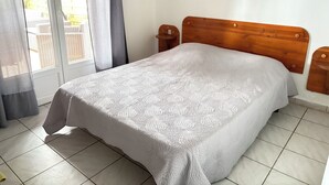 Makuuhuone, jossa on sänky, puinen pääty, yöpöytä ja ikkuna, jossa on verhot.