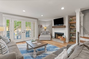 A living room with a sofa, a coffee table, a fireplace, and a television. - Walk to Beach & Restaurants | 4 Levels | Rooftop Deck | Remodeled & Updated Throughout (St. Simons Island)